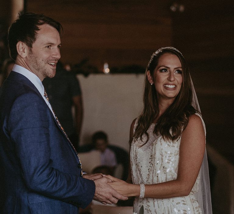 Bride & groom stand together and hold hands on their wedding day during ceremony