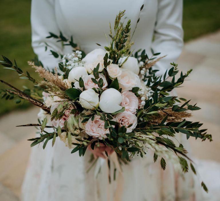 Romantic pink rose and white peony wedding bouquet with foliage 