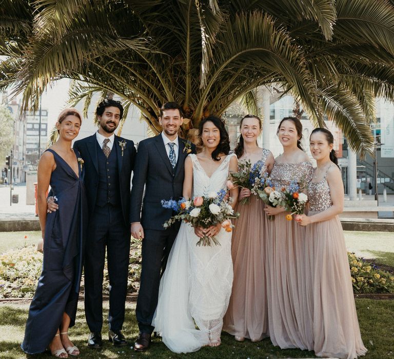 Bride and groom and their wedding party. The bride is wearing an Eliza Jane Howell gown, the bridesmaids are wearing blush dresses with sequin detail and the groom and groomsman and groomswoman are wearing navy blue