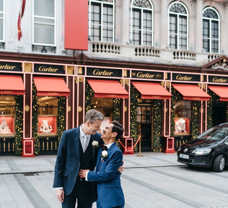 A gay couple embrace in the streets of London for wedding portraits. 