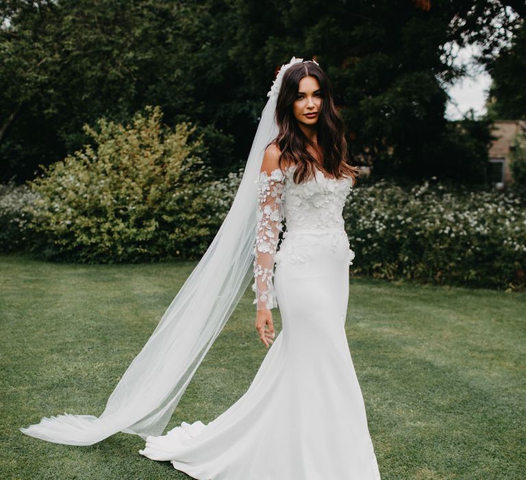 Bride in an A line wedding dress with strapless appliqué bodice and matching appliqué cathedral length veil 