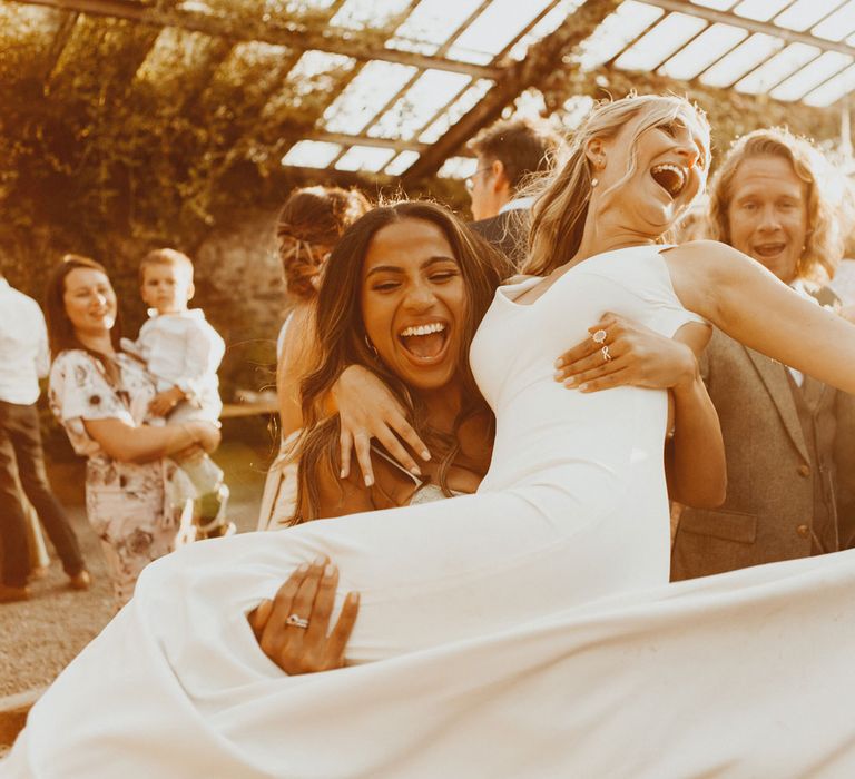 Bride in white Made With Love wedding dress is swung around by guest during golden hour at the glasshouse at Anran Devon