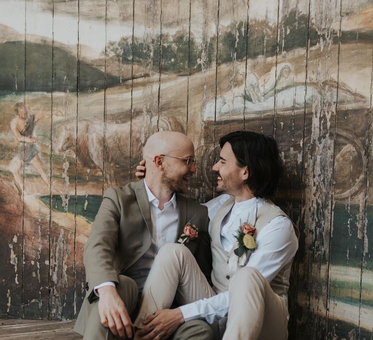 Grooms in taupe and beige suits sitting on the bandstand at The Larmer Tree bandstand 