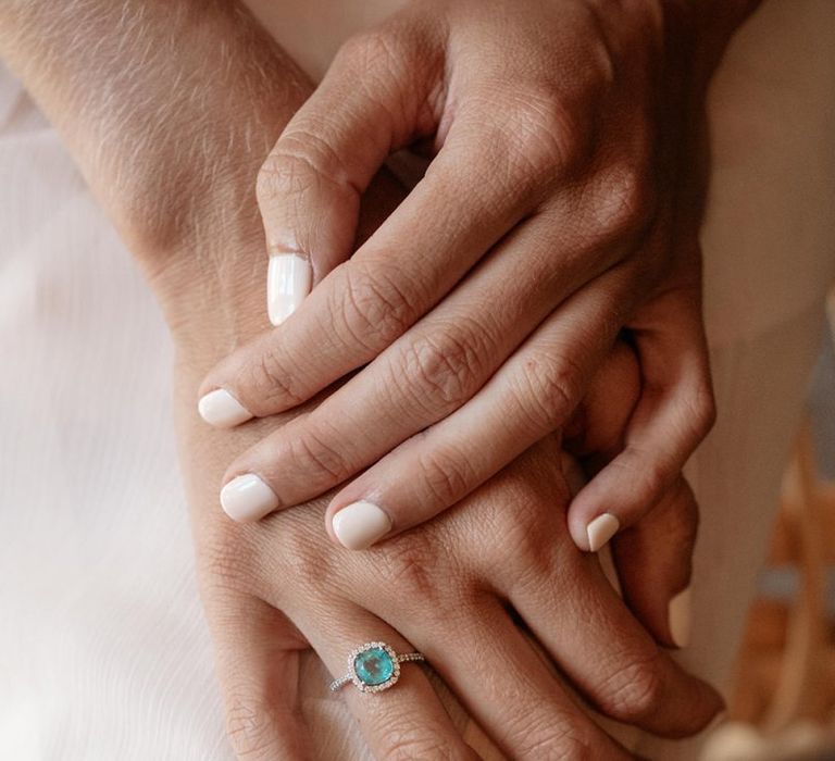 Bride wears neutral nail varnish and square green stone engagement ring