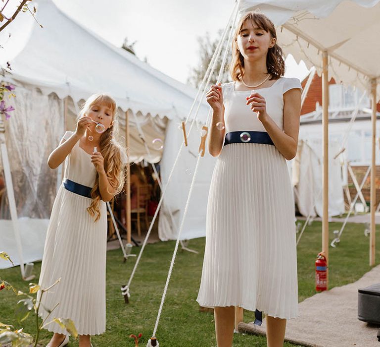 Bridesmaids blow bubbles outside marquee for garden wedding