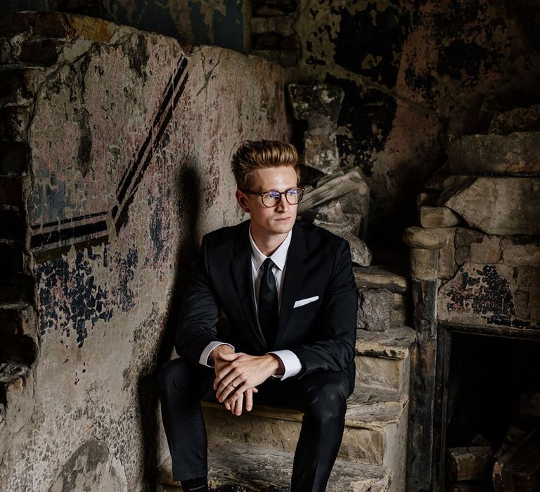 Urban Groom sits on stone brick staircase in empty Asylum London chapel 