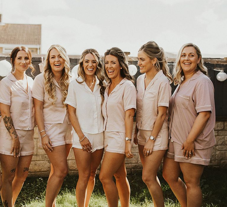 Bride stands with her bridesmaids who wear matching pyjamas 