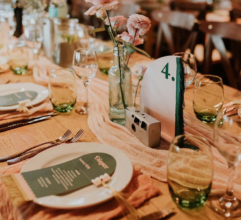 Wedding tablescape complete with disposable camera and retro vibe with neutral toned table runner through middle of table