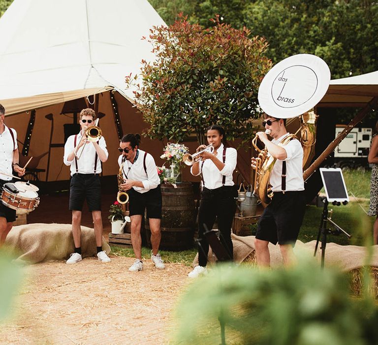 Brass band play outdoors in front of tipi on wedding day