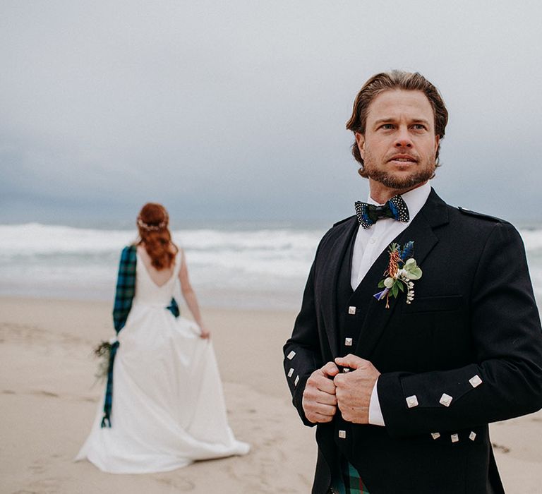 Groom in a black jacket, waistcoat and bow tie with tartan kilt at Big Sur beach