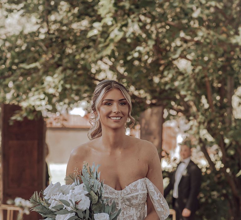 Bride walks down the aisle in custom wedding gown on her wedding day