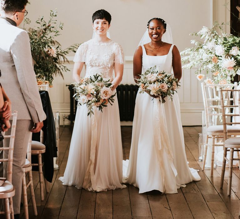 Romantic Elmore Court wedding with two brides holding pink, white and green wedding bouquets tied with ribbon 