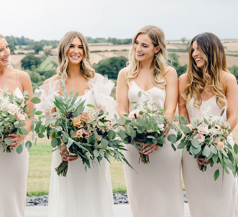 Neutral bridesmaid dresses with bride in Halfpenny London dress with floral bouquets