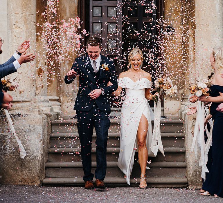 Groom in blue checkered suit and bride in off the shoulder sweetheart front slit wedding dress have their confetti exit 