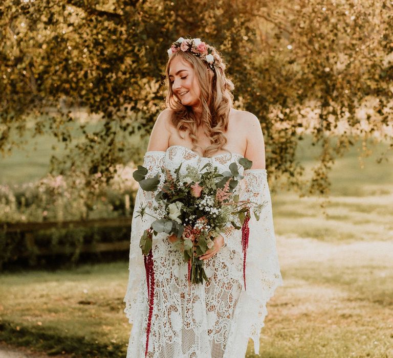 Stunning bride in lace medieval wedding dress with custom sleeves, a flower crown, pink, red and white wedding bouquet