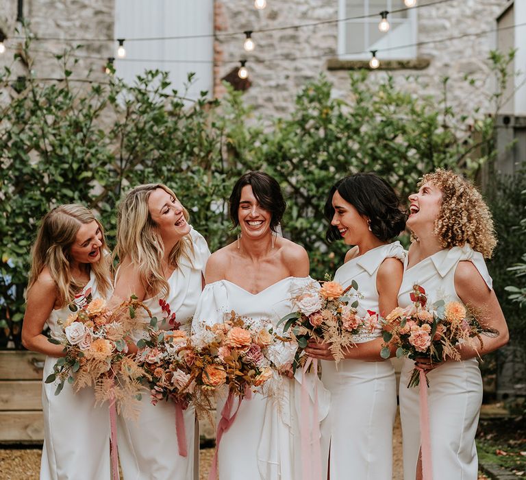 White one shoulder bridesmaids dresses with bow and bride in puff sleeve fitted wedding dress with autumnal bouquets