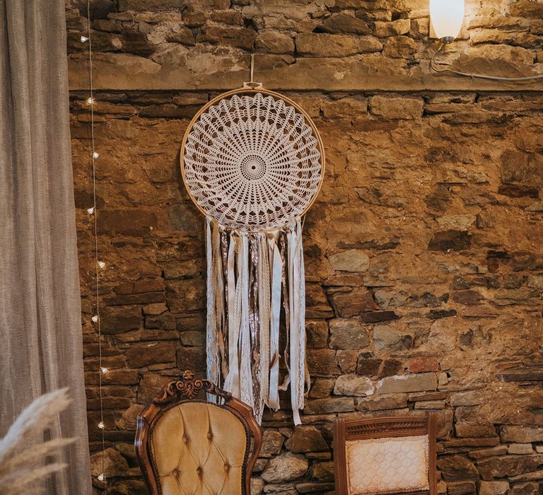 Mismatching chairs at the altar for thr bride and groom with boho macrame dream catcher style decor 