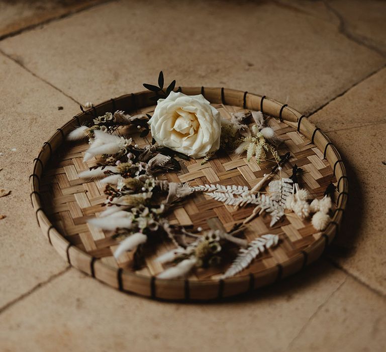 Woven tray with dried flower boutonnières and white rose buttonhole for grooms and groomsmen