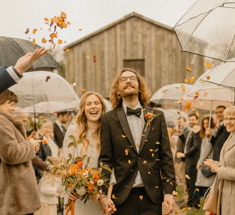 Orange autumn leaf confetti exit for bride and groom at rustic barn wedding