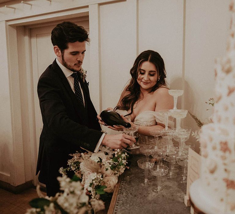 Bride and groom pour their own champagne tower for their romantic wedding at Millbridge Court