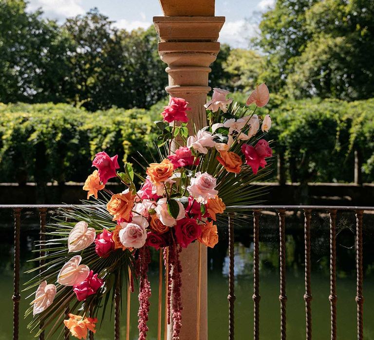 Bright floral bouquet complete with roses tied to pillar in front of lake 