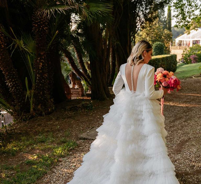 Bride wears Milla Nova wedding gown with tulle skirt and holds bright floral bouquet 