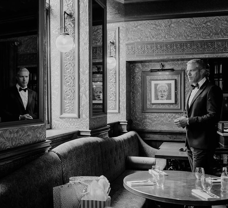 Groom in black tie stands as he prepares for the wedding day 