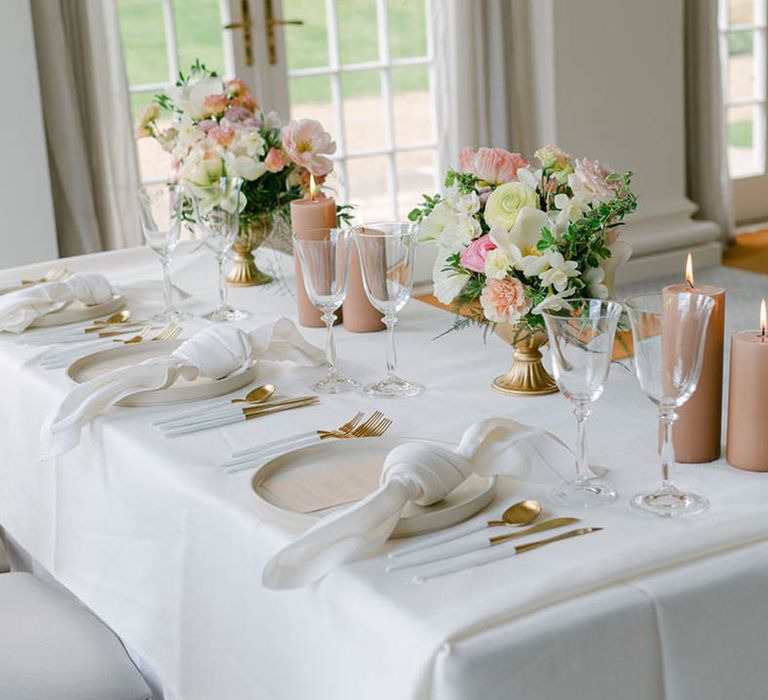 Intimate sweetheart table with neutral and beige colour palette including pillar candles and gold cutlery 