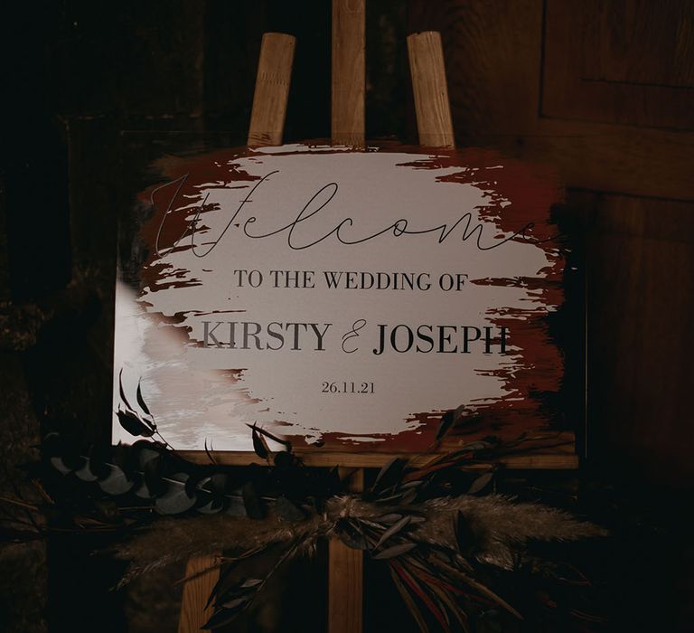 Welcome wedding sign on wooden easel surrounded by green foliage at Pentney Abbey