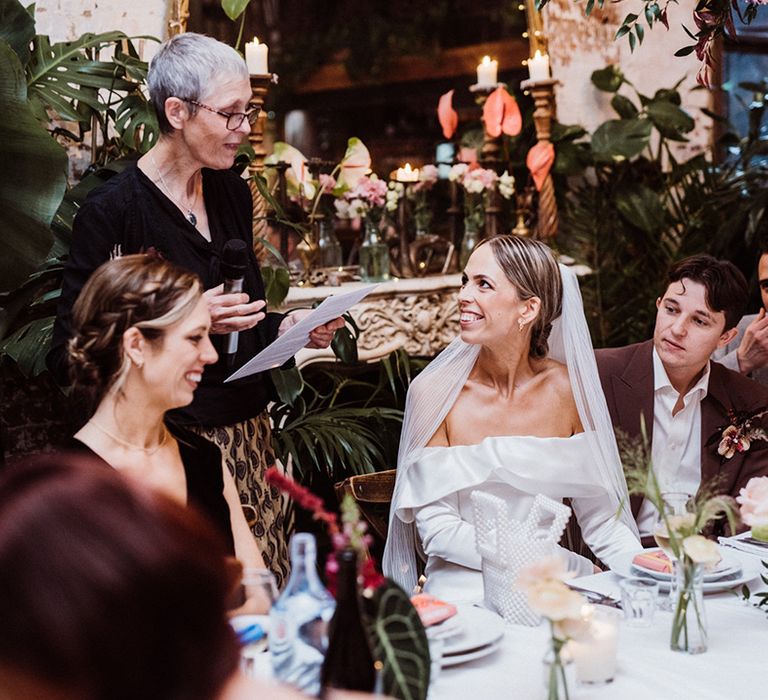 Mother of the bride reads out a speech as everyone listens 