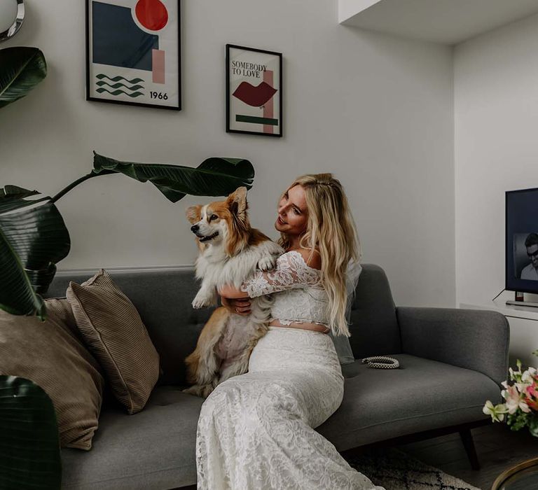 Bride in lace boho two piece holding corgi puppy getting ready for stylish wedding