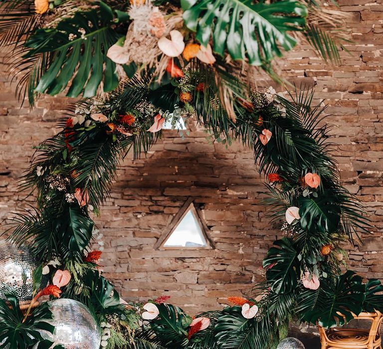 Tropical wedding flower arranged moongate with pink and red anthuriums and palm leaves 