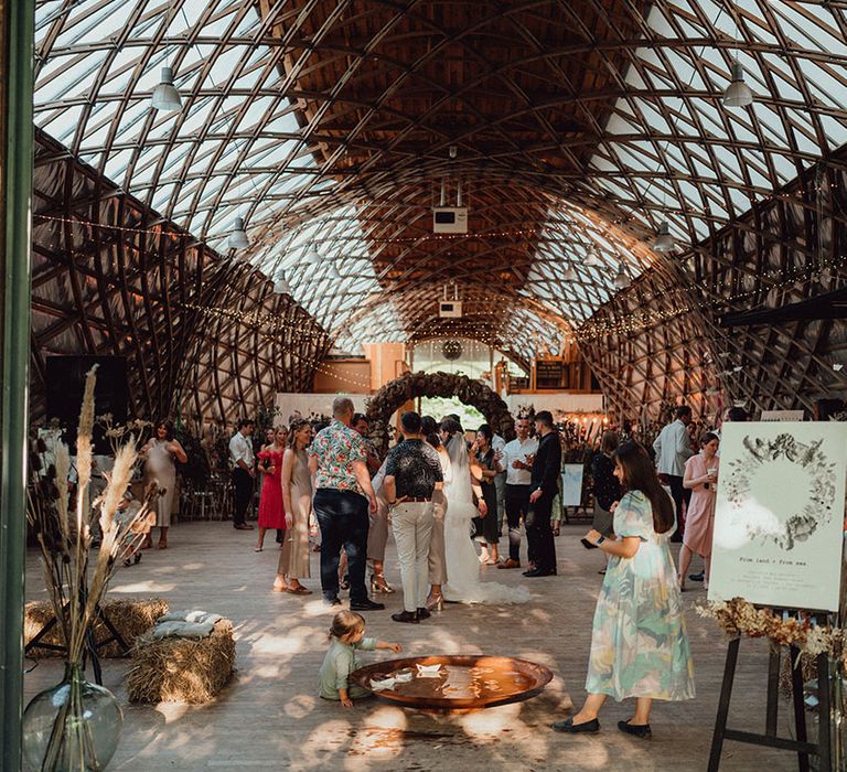 The Gridshell at Weald and Downland Living Museum venue with boho decor including pampas grass, hay bales, flower arch, and wedding signage for wedding baptism