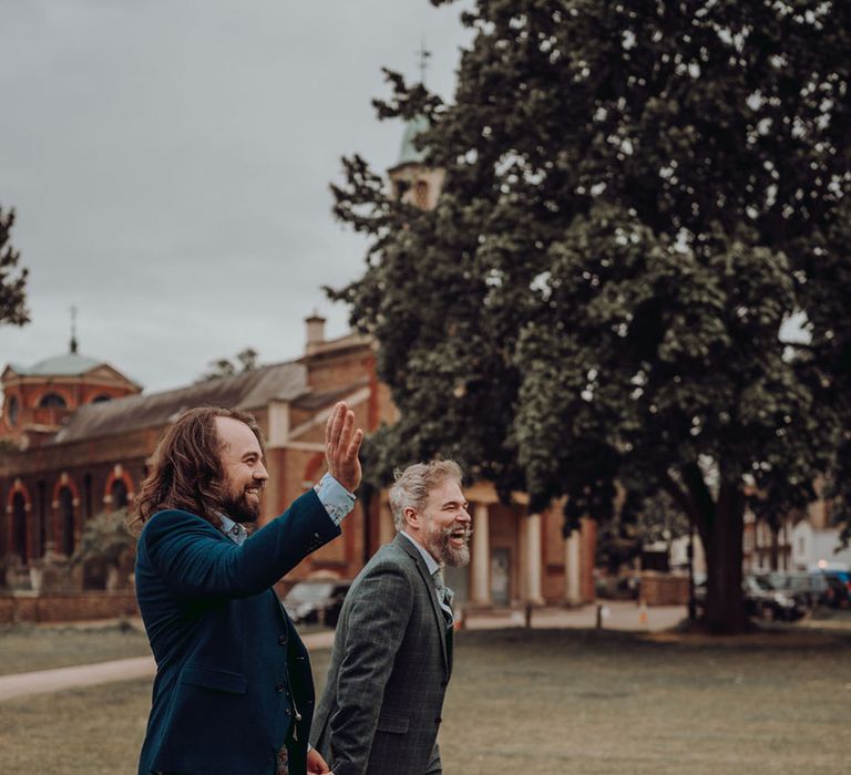 Grooms walk outdoors across the ground of Kew Gardens for LGBTQIA+ wedding 