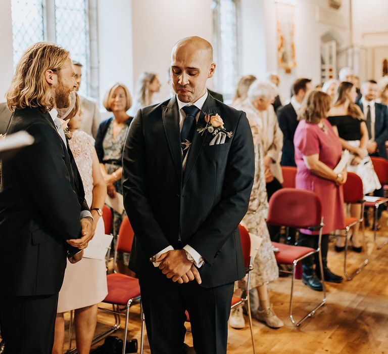 The groom begins to tear up as he sees the bride walking down the aisle for their traditional church wedding ceremony 