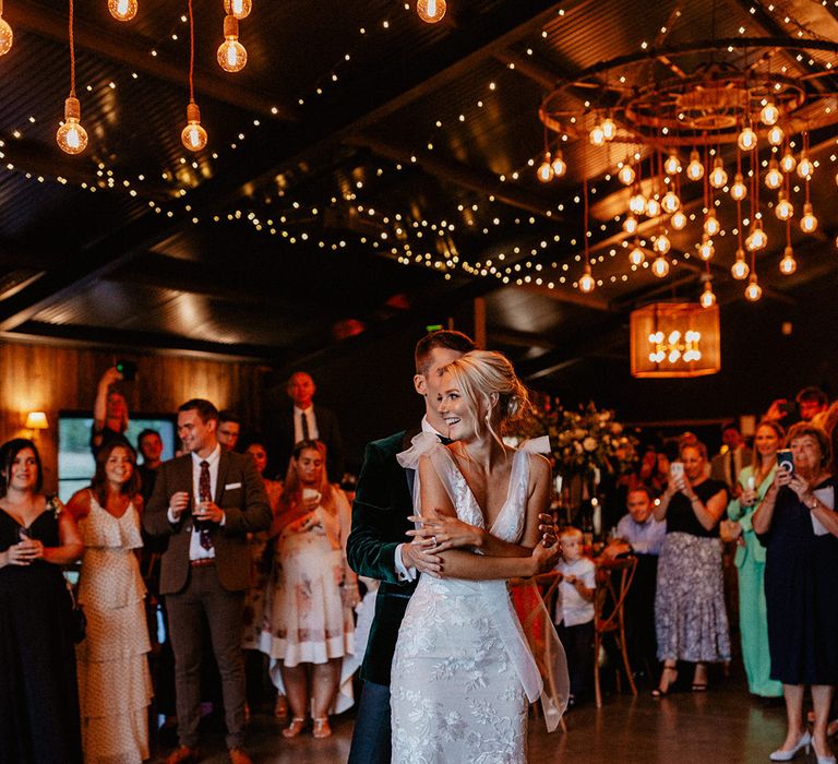 Enchanting rustic luxe Silchester Farm wedding with festoon light installations with the bride and groom sharing their first dance together 