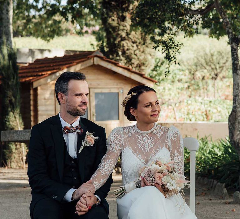 bride in a boho wedding dress and groom in a black suit holding hands at their outdoor wedding ceremony at Porto Vineyards Portugal