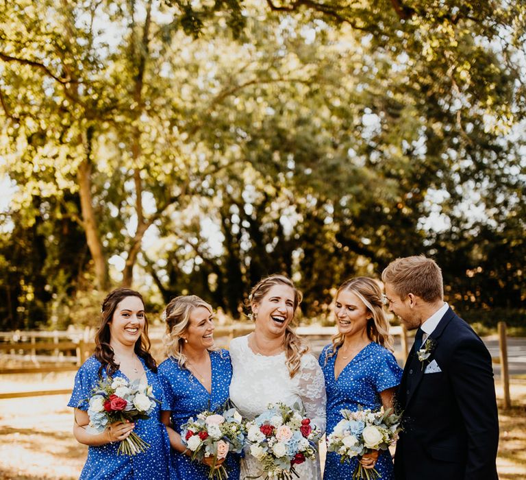 Bright blue spotted wrap midi bridesmaid dresses with the bride in a long sleeve lace wedding dress 