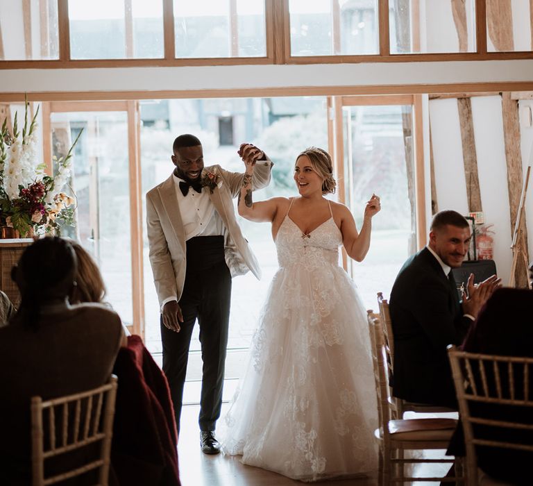 The bride and groom enter the wedding reception together with their joint hands raised to the sky 