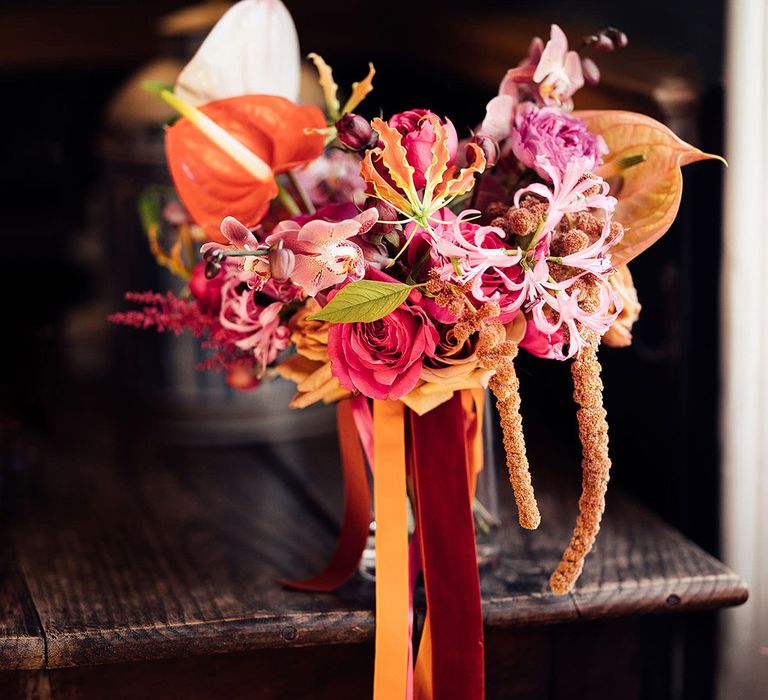 Bright pink and orange wedding bouquet with roses, orchids, anthuriums and other tropical flowers