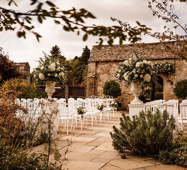 outdoor wedding ceremony at Caswell House with white chairs and white and green urn wedding flower arrangements 