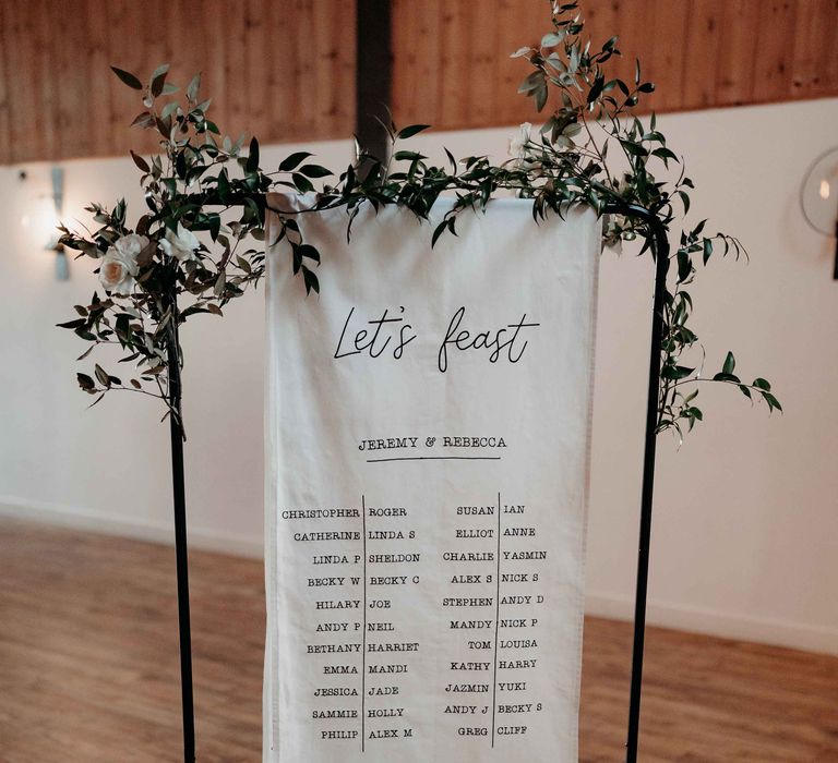 Hanging fabric embroidered table plan with green foliage 