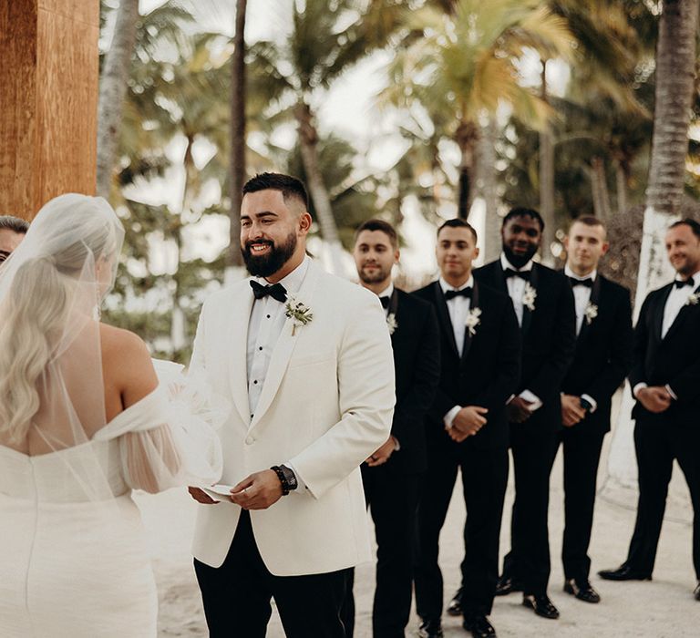 bride in a strapless wedding dress with wavy ponytail wedding hairstyle exchanging vows during the beach wedding ceremony 