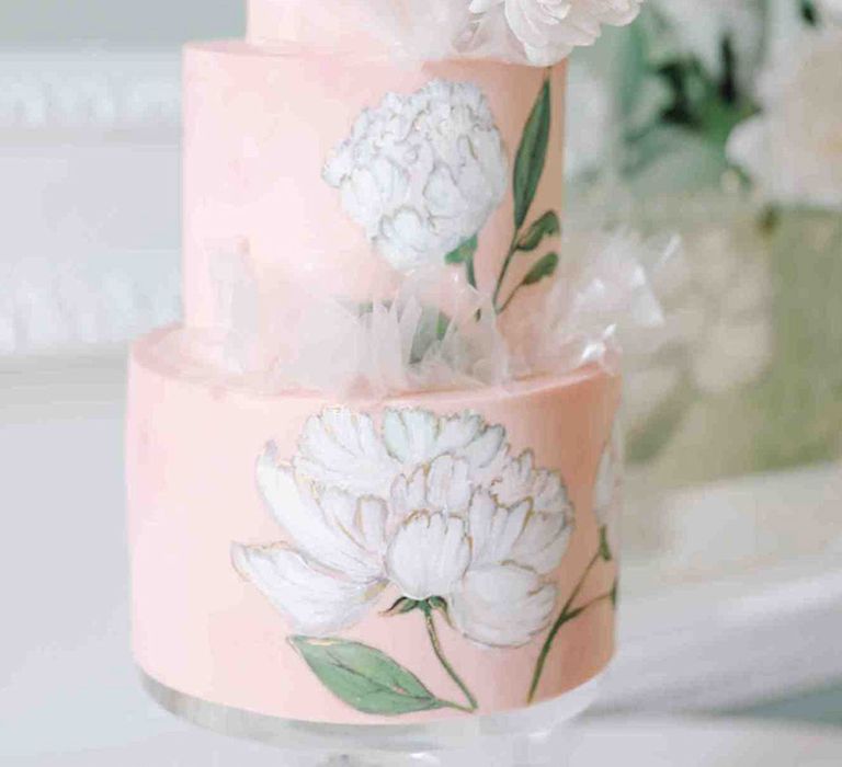 Pink wedding theme with pastel pink iced wedding cake and large white iced flower decoration 