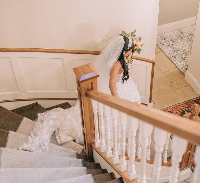 Bride in floral lace Savin London wedding dress walking down the stairs 