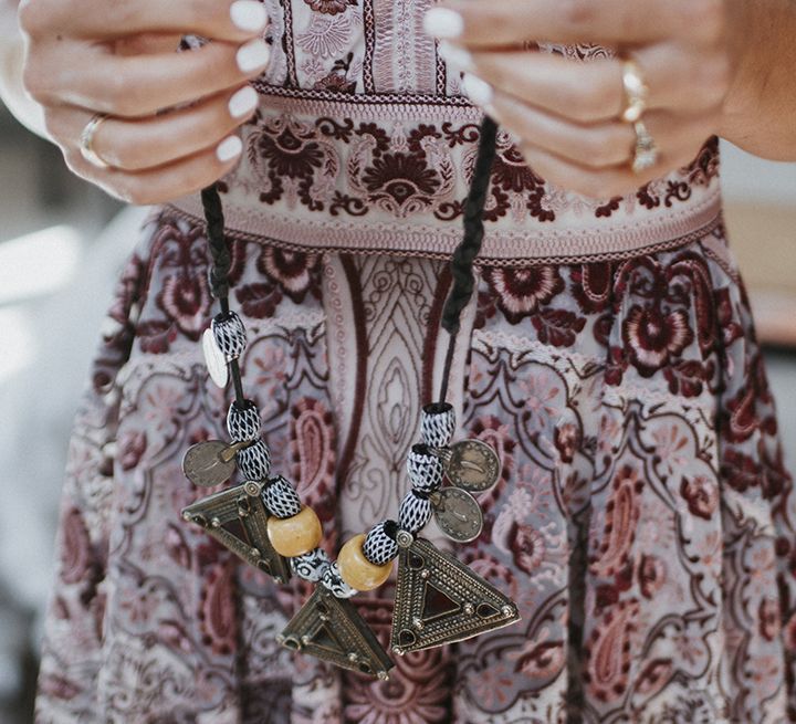 Bride with white wedding nails holding aztec wedding necklace