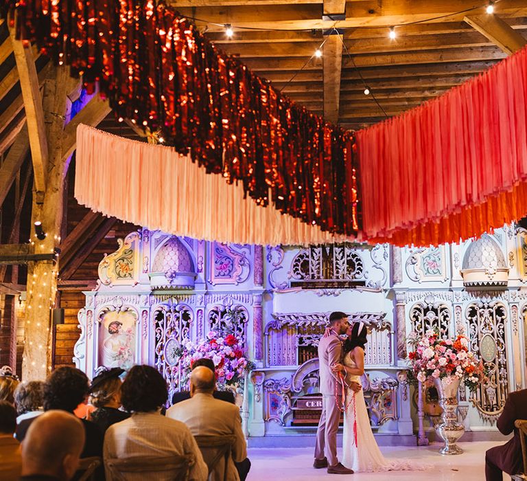 The bride and groom share their first kiss as a married couple at Preston Court wedding venue with colourful streamer decorations 