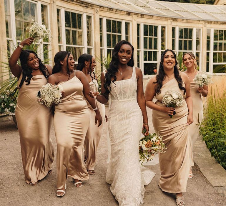 Bridal party I champagne satin bridesmaid dresses walking with the bide in a beaded wedding dress 