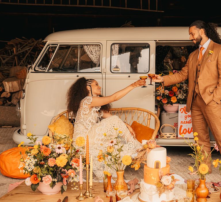 VW camper van wedding transport with orange and yellow wedding flower decorations, banner signs, and three tier iced wedding cake 