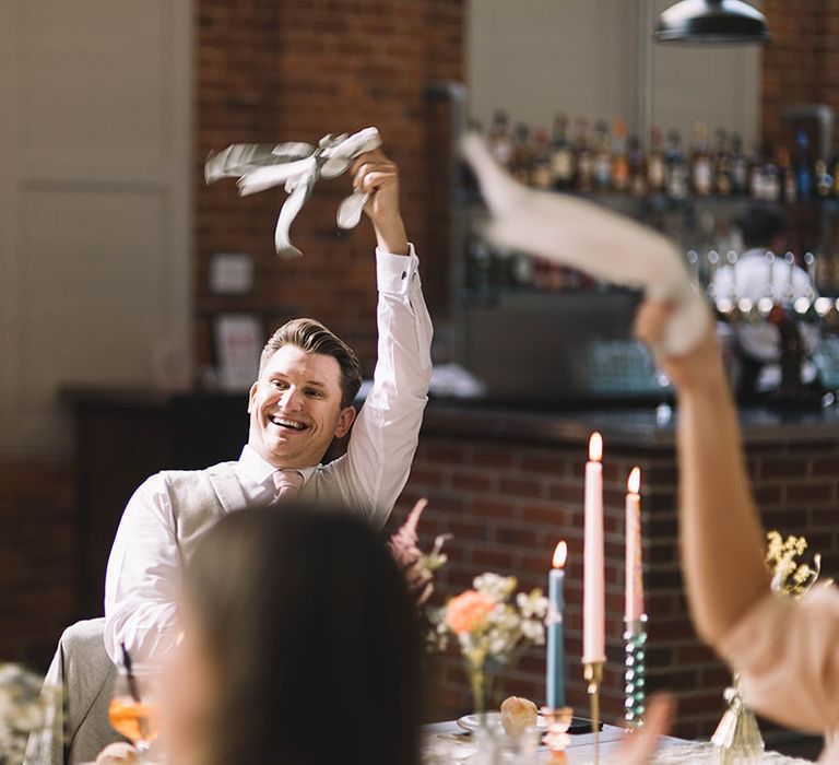 Wedding guest smiles brightly as he twirls the wedding napkin to greet the bride and groom 